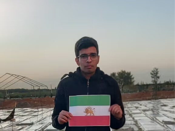 Reza Mohammadhosseini, a monarchist political prisoner held in Qezel Hesar Prison, holding the Lion and Sun flag